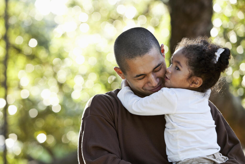 Hispanic father and daughter hugging at park